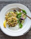 Cauliflower, Quinoa, Corn Cakes with Yogurt Mint Sauce on plate with salad and lemon wedge