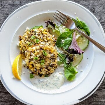 Cauliflower, Quinoa, Corn Cakes with Yogurt Mint Sauce on plate with salad and lemon wedge