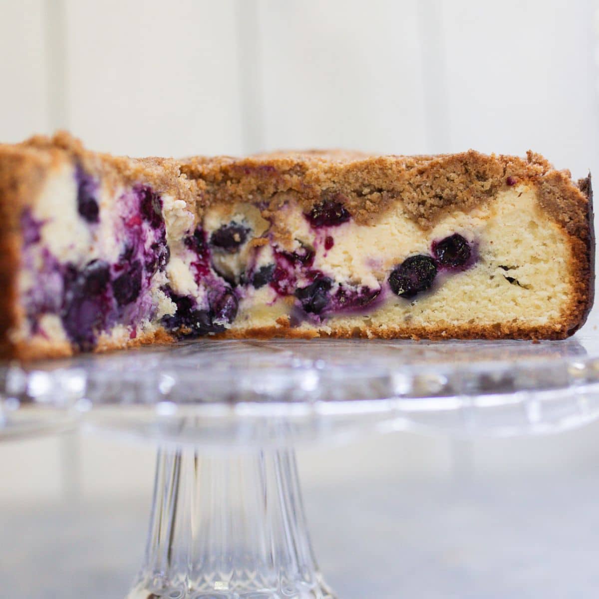 Blueberry cheese crumb cake cut on a cake stand.