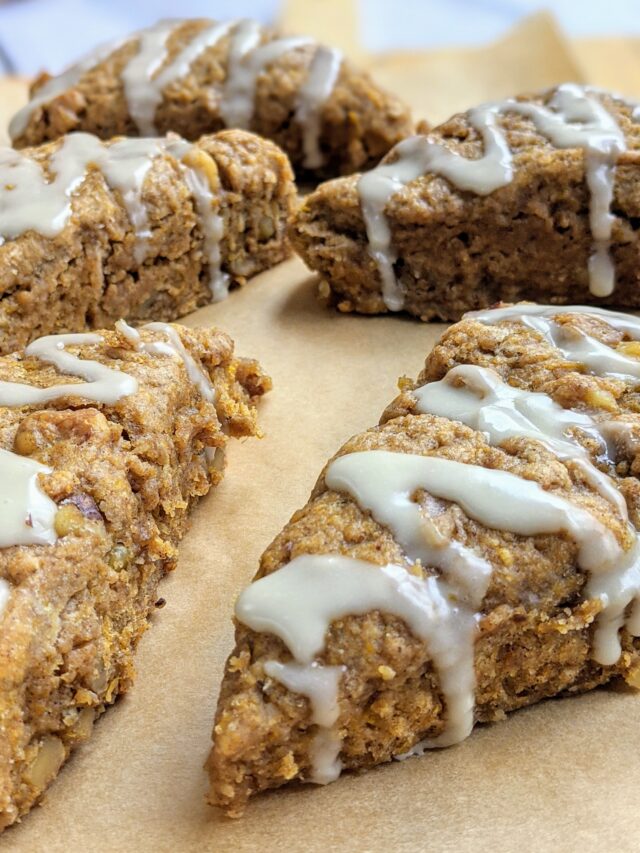 Pumpkin Walnut Scones on a sheet of parchment paper with icing drizzled on top