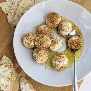 lemon goat cheese balls in dukkah on a plate with a spoon