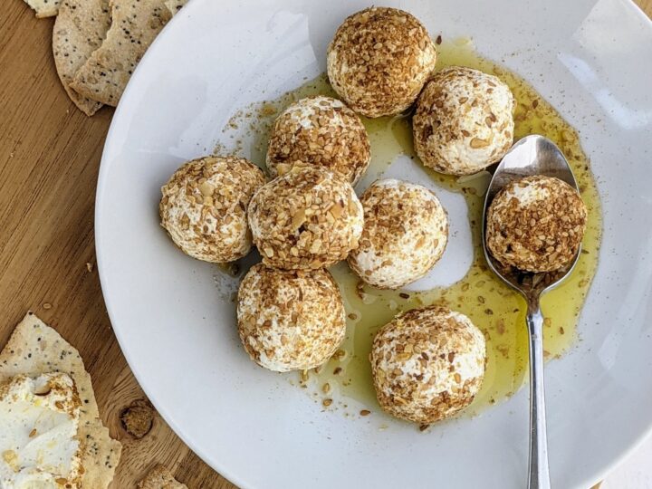 lemon goat cheese balls in dukkah on a plate with a spoon