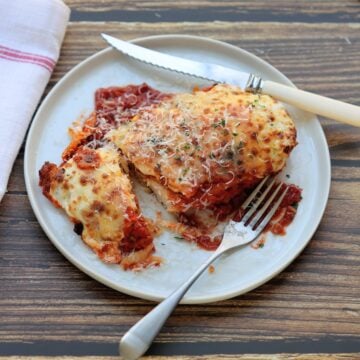 one piece of crispy chicken parmesan with fork and knife