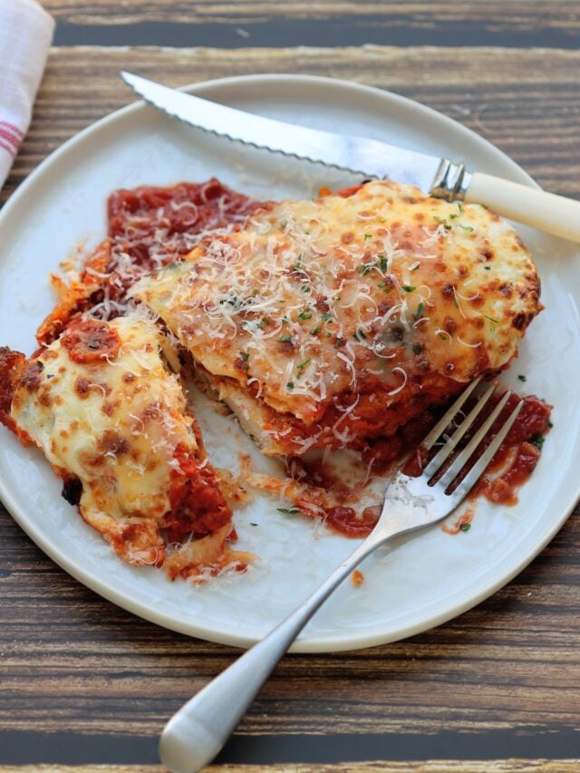 one piece of crispy chicken parmesan with fork and knife