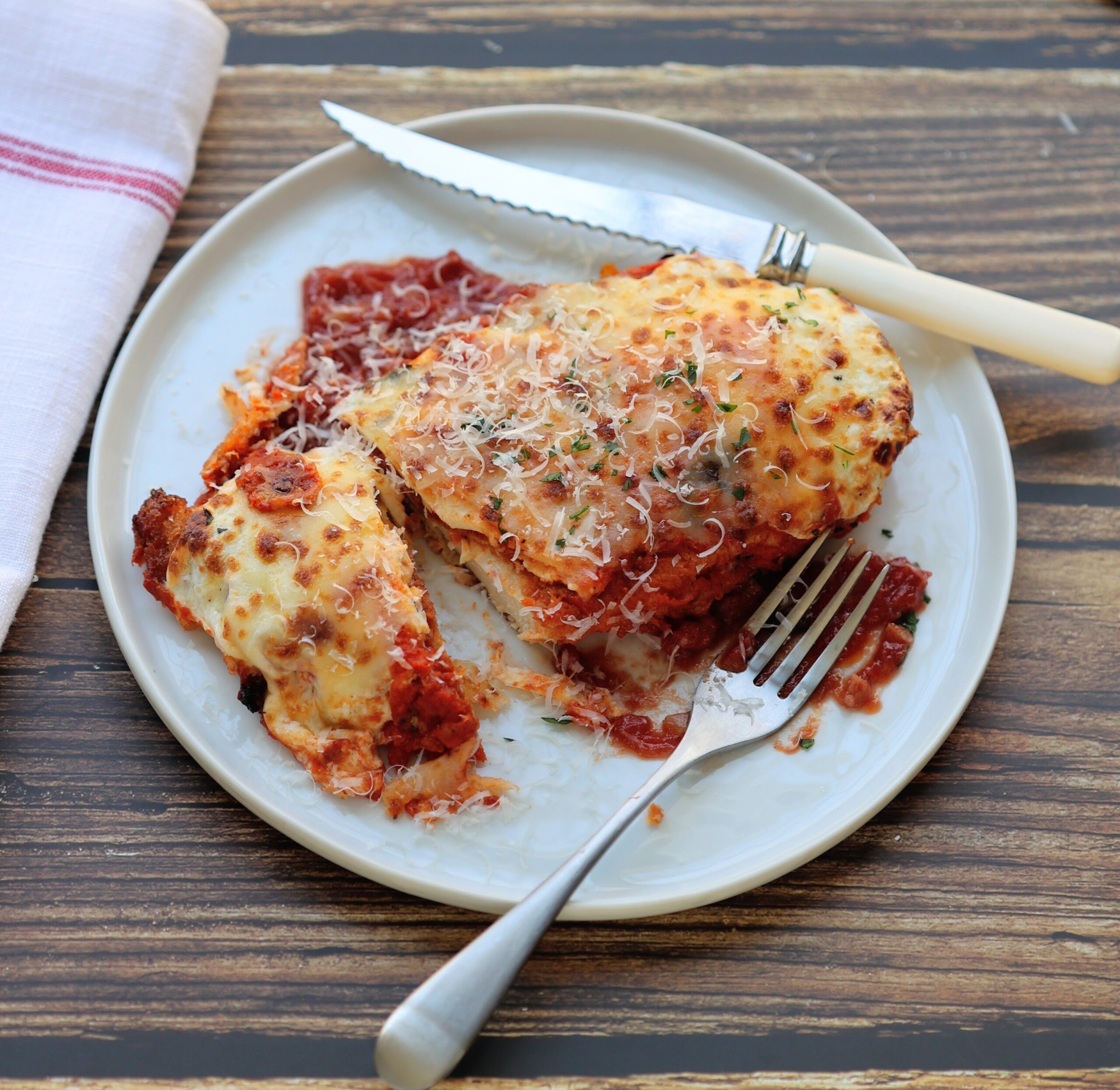 chicken parmesan cut open on a dinner plate with knife and fork