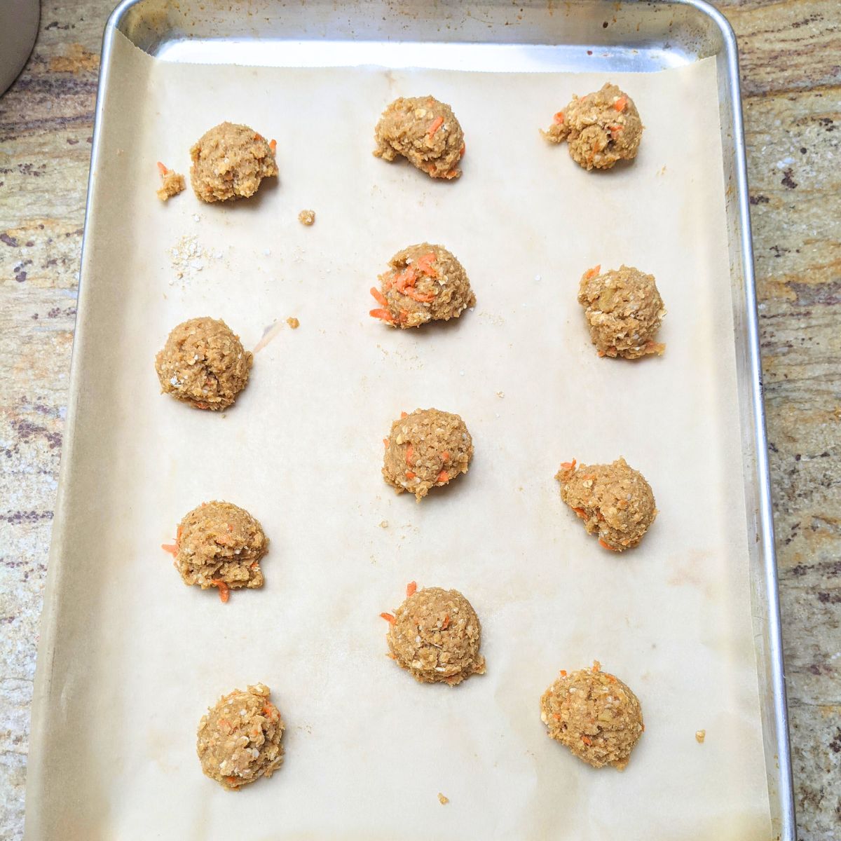 Unbaked carrot cake cookies on baling sheet.