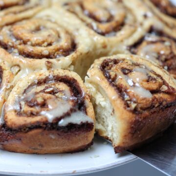 Cinnamon Buns out of pan and one being lifted out