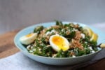 bowl of kale salad with toasted garlicky crumbs, crumbled feat, and 2 halves of a sift-boiled egg