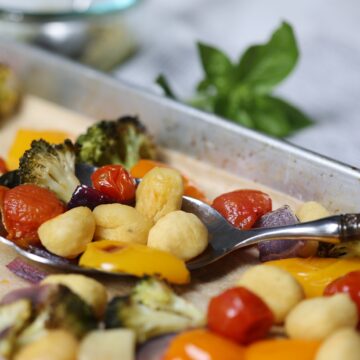 gnocchi with vegetables and pesto on a sheet pan with a serving spoon
