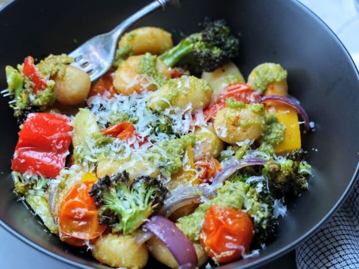 Bowl of sheet pan gnocchi with vegetables and pesto.