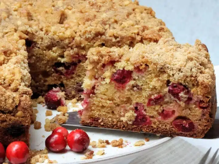Cranberry Streusel cake on cake stand with slice bing removed.