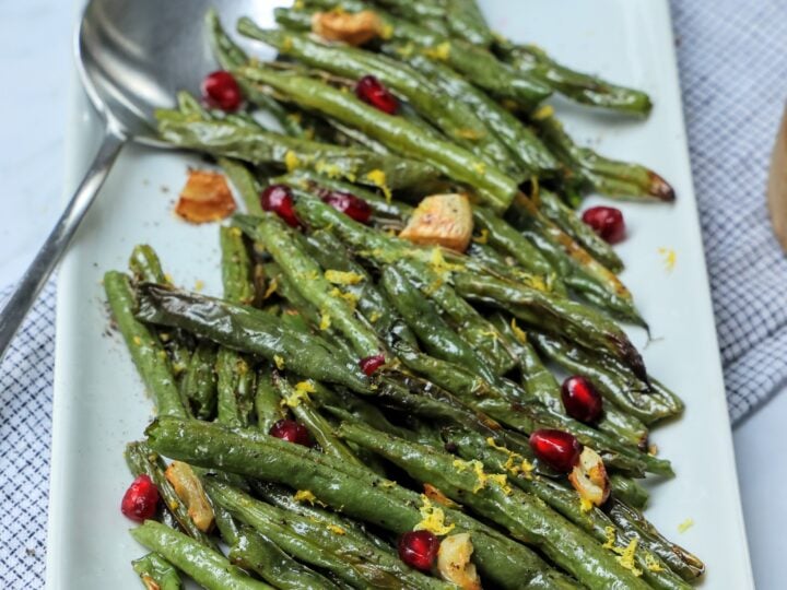 Serving platter of roasted green beans with garlic and pomegranate seeds