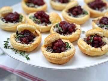 servoing platter with mini mushroom tarts with lingonberry sauce garnished with sprig of fresh thyme