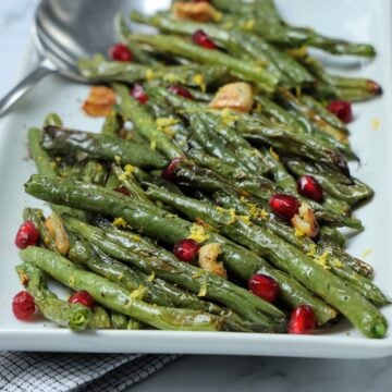 Platter and spoon with Roasted Green Beans and Garlic with Pomegranate Seeds