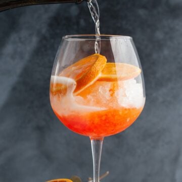 Glass of spritz Veneziano (aperol sprtiz) with sparkling wine being added.