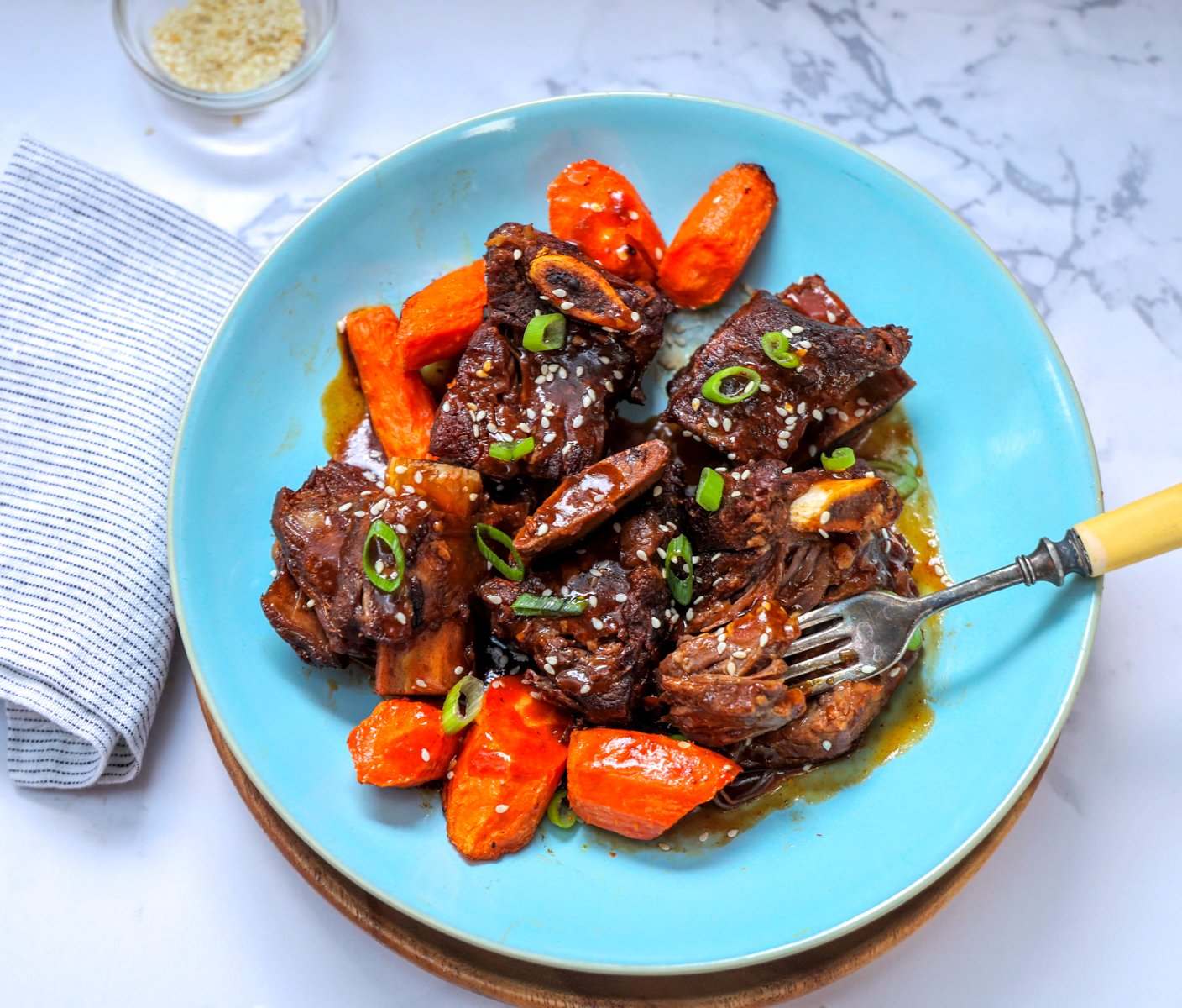 Blue dinner plate with Asian short ribs and carrots.