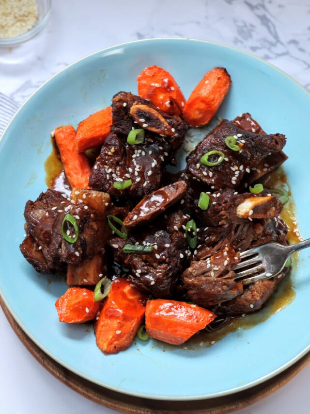 overhead shot of shallow bowl wth asian short ribs and carrots and fork in bowl.