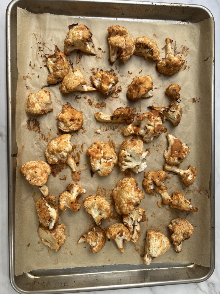 Oven roasted cauliflower bites on a parchment lined baking tray