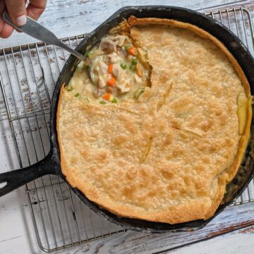 Baked chicken pot pie on wire rack with spoonful being removed.