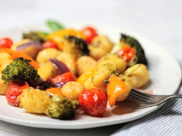 Plate with sheet pan gnocchi with pesto and vegetables with forkful.