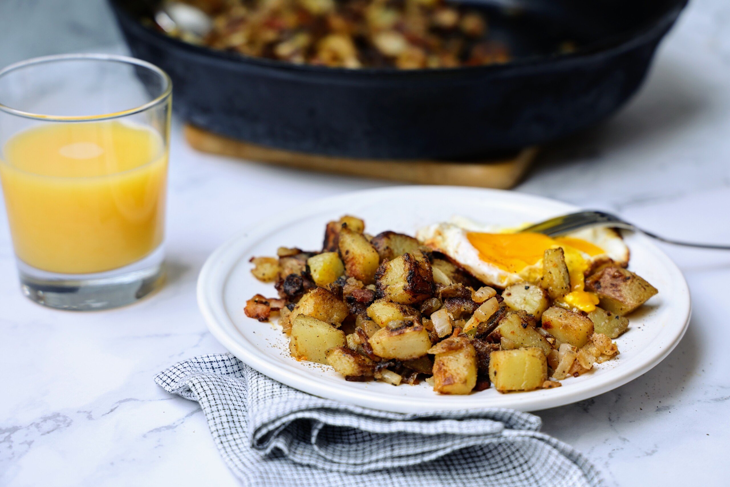 Skillet breakfast potatoes (home fries) on plate with over-easy egg on top.