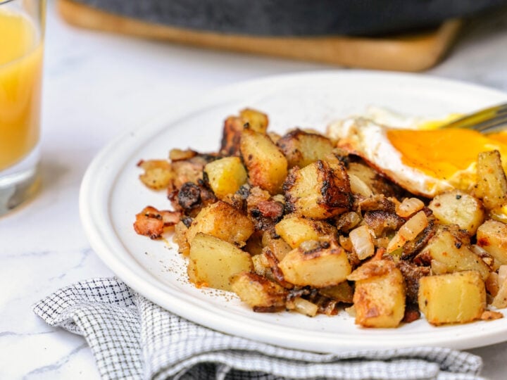Plate of skillet breakfast potatoes with over easy egg on top.