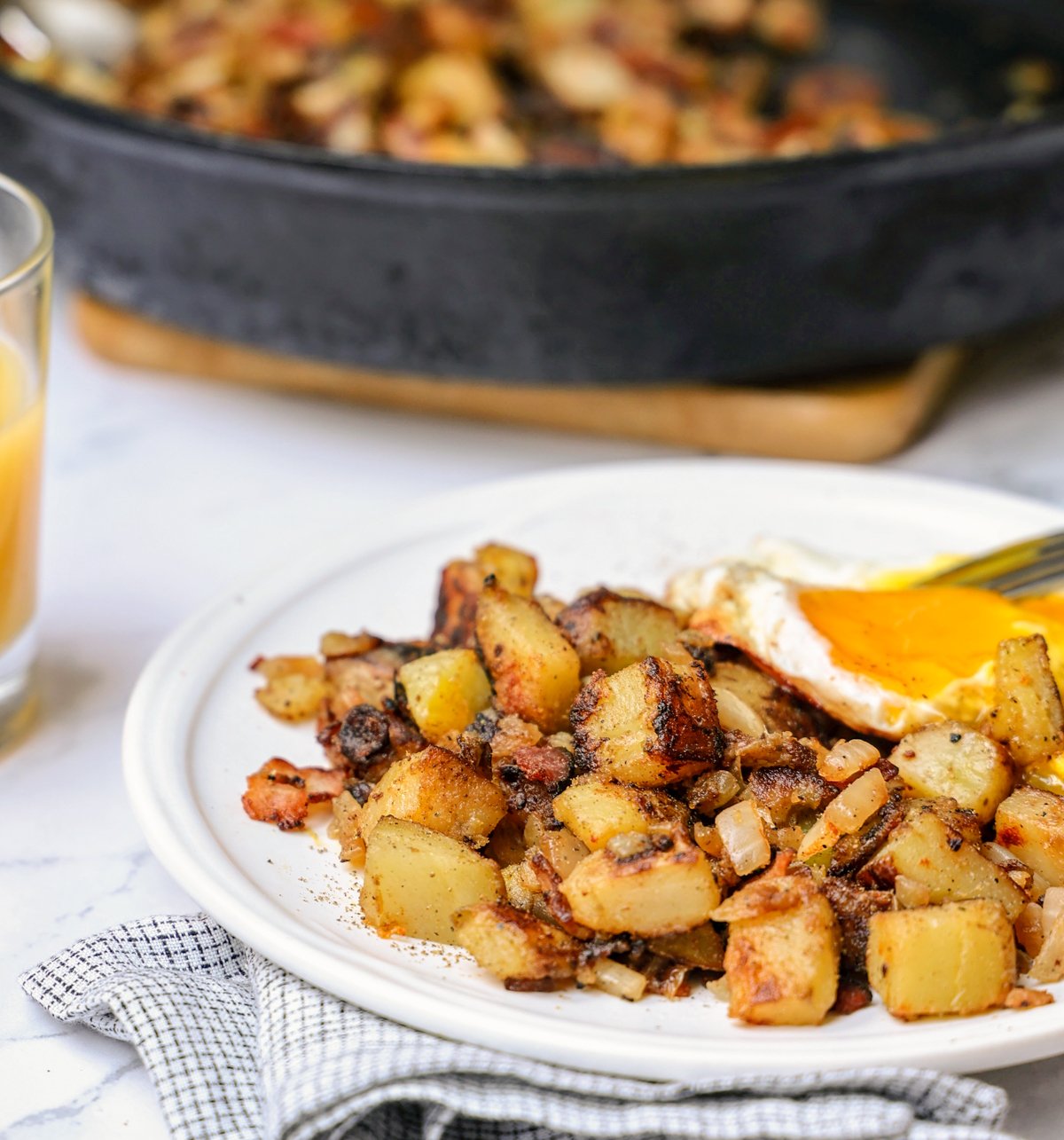 plate with skillet breakfast potatoes and an over easy egg on top.