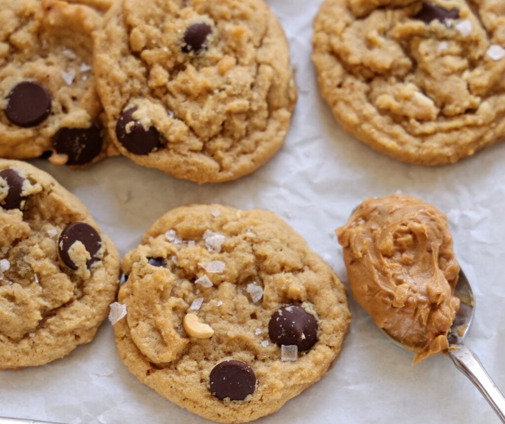 Close up shot of freshly baked cookies. A spoon of peanut butter sits next to them