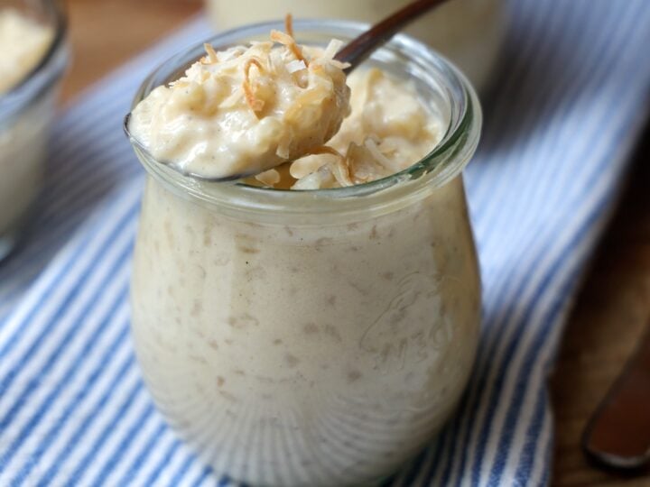 small glass jar filled with coconut rice pudding with spoonful set on top.