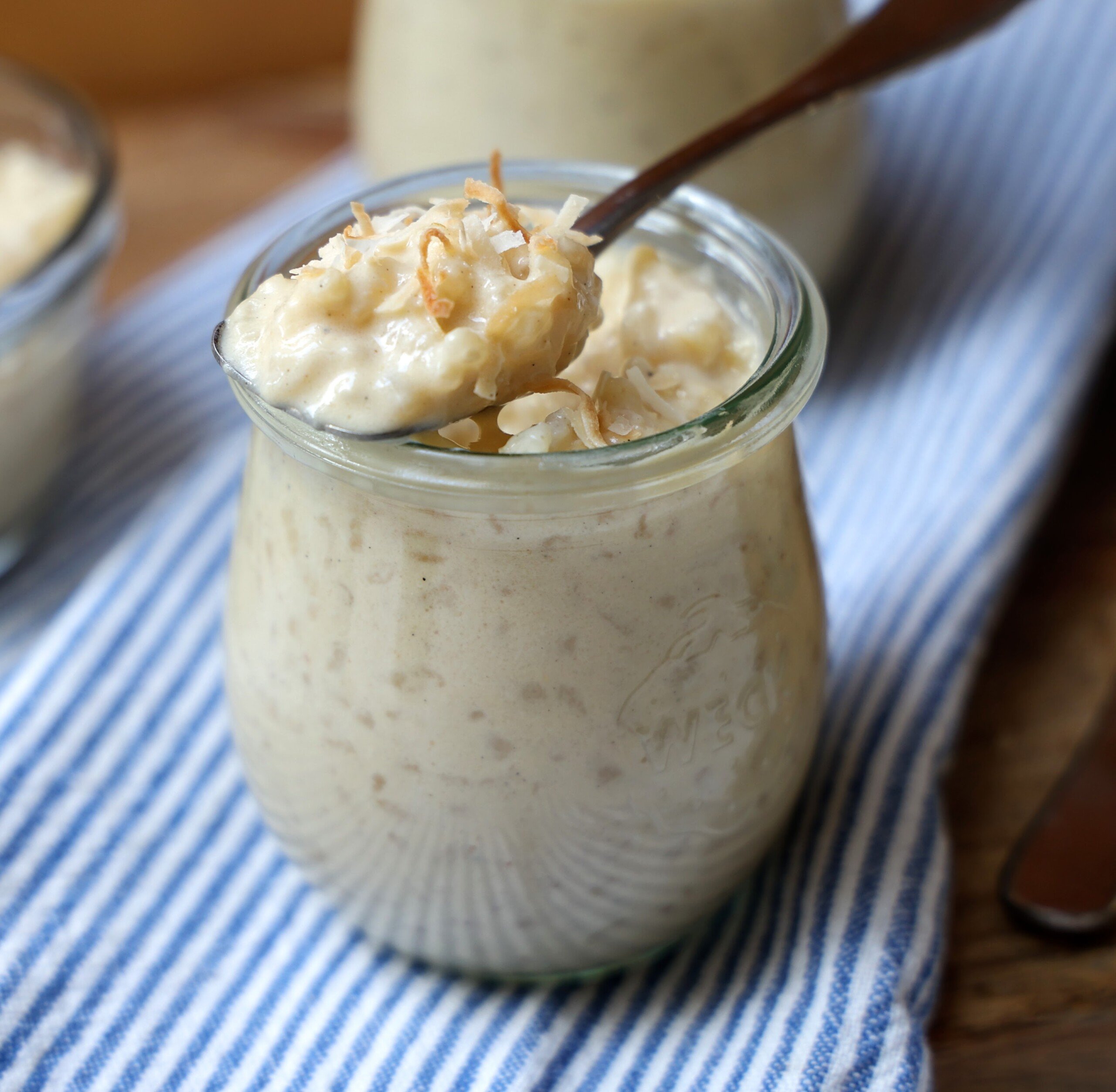 Close up of small jar with coconut rice pudding garnished with toasted coconut.
