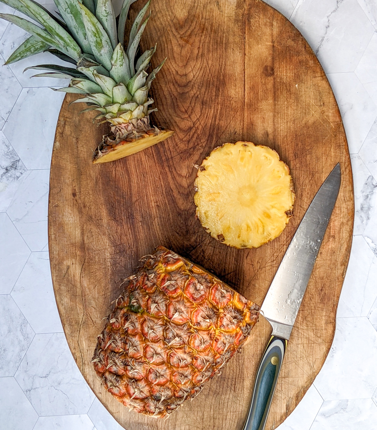 Cutting the top and bottom off of a fresh pineapple.