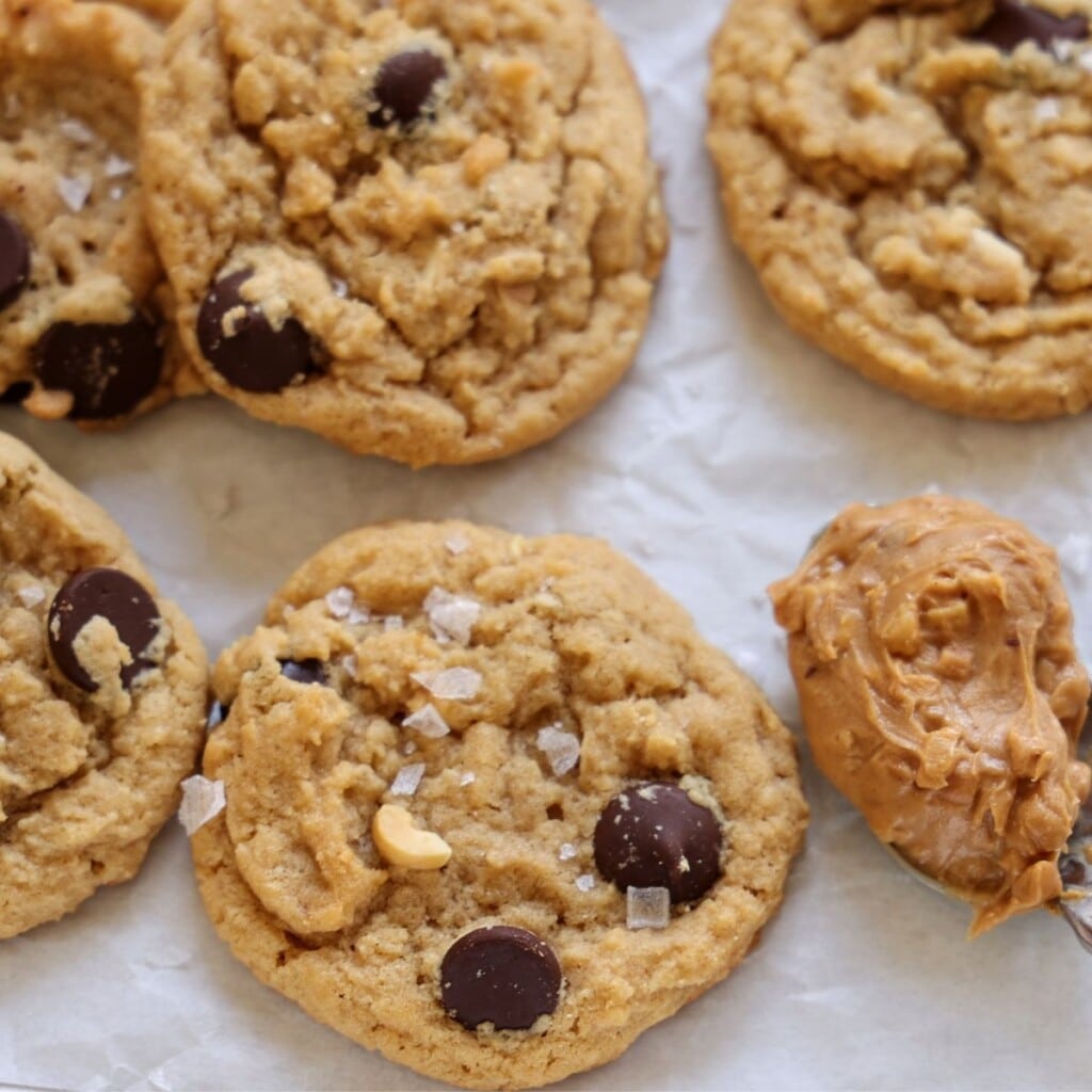 Peanut Butter Chocolate Chip Cookies on baking sheet topped with flakey sea salt.