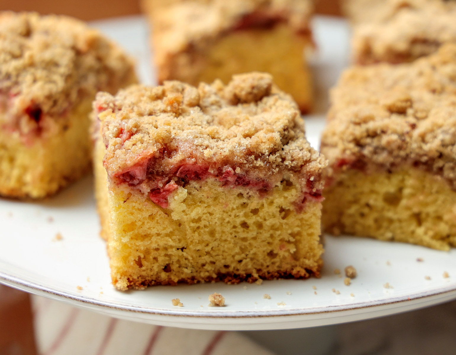 Slice of Strawberry Coffee Cake on a serving platter with pieces in background.