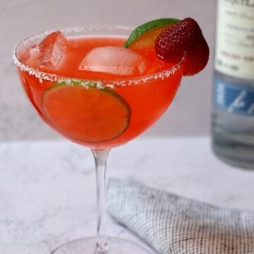 Strawberry margarita in a salt-rimmed stemmed glass.