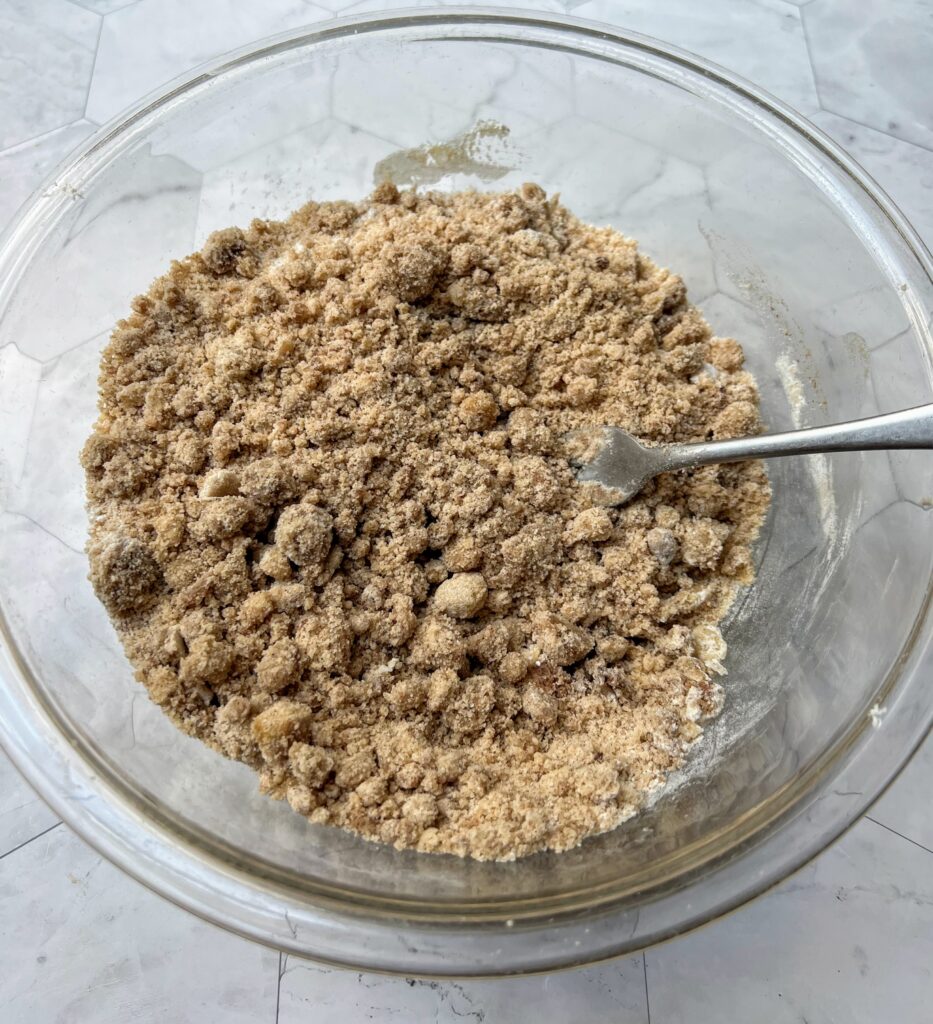 Glass bowl of crumb topping: flour, butter, brown sugar, granulated sugar, salt, and cardamom