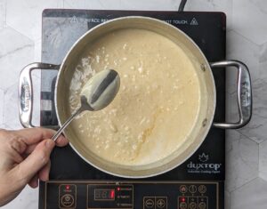 The coconut rice pudding has thickened to coat the back of a spoon signifying it is done