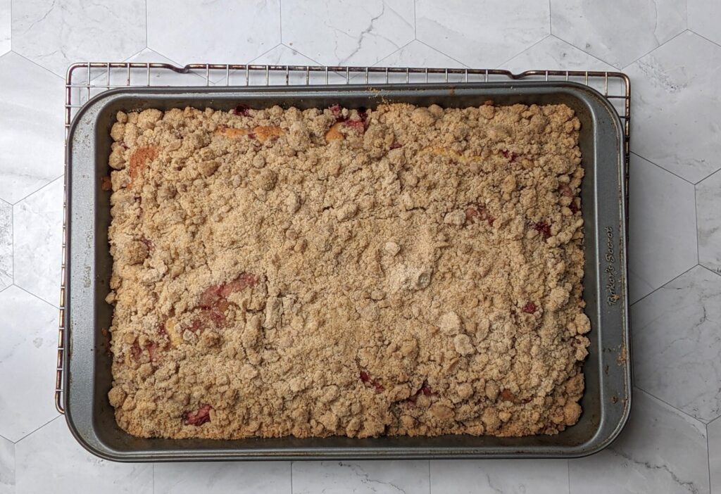 Overhead shot of baked strawberry crumb cake cooling on a wire rack