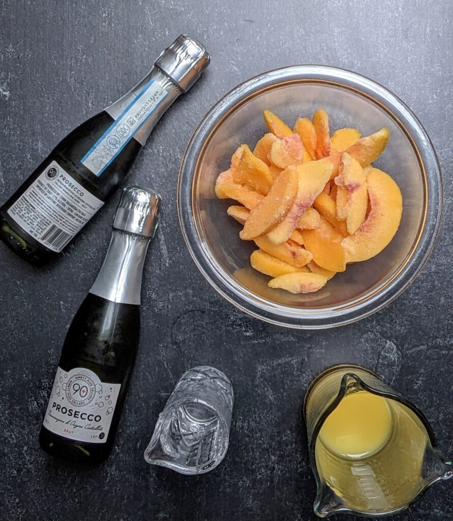 overhead shot of ingredients: frozen peaches, prosecco, peach nectar, lime juice