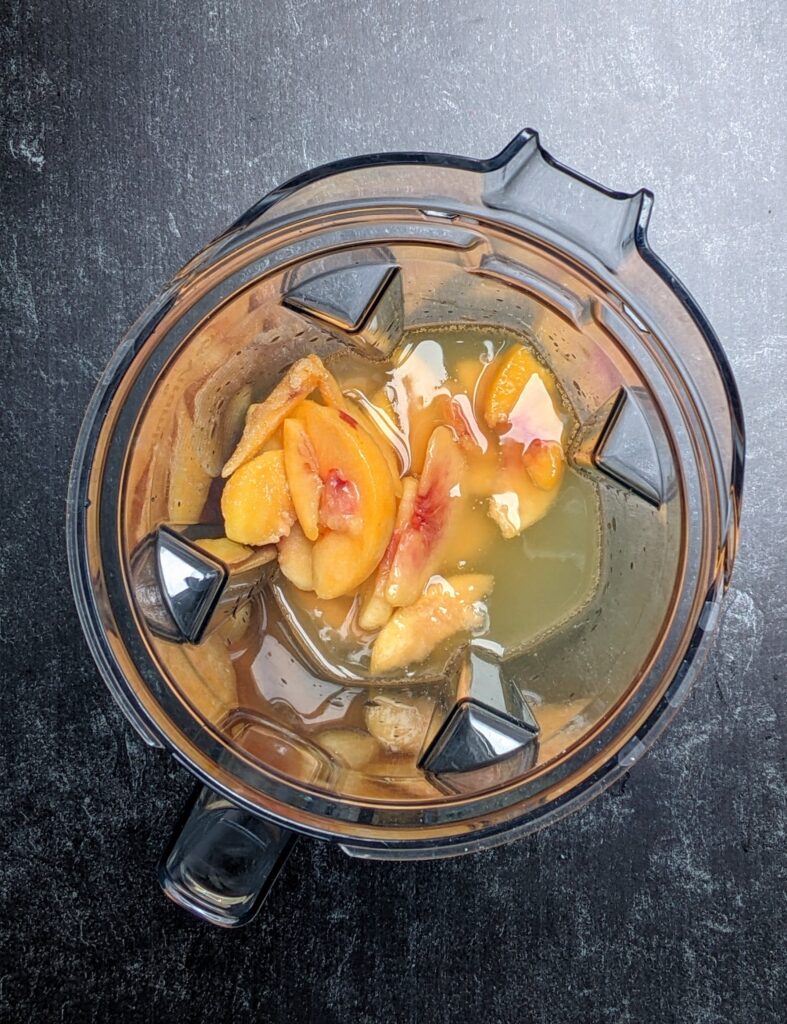 overhead shot of blender with frozen peaches, fruit nectar, vodka, prosecco, 