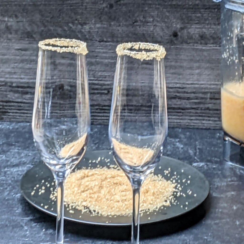 two champagne flutes rimmed with sugar.