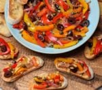 Bowl of peperonata surrounded bt toasted bread slices topped with it.
