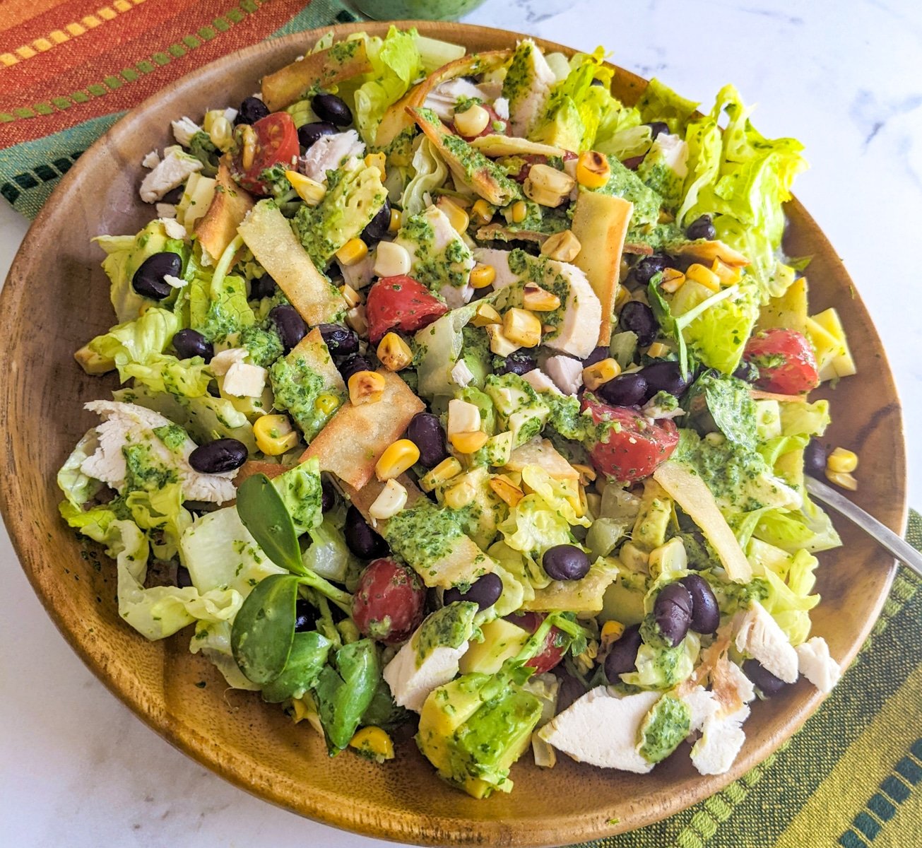 Wooden bowl with Santa Fe Salad with chicken set on a colorful Mexican napkin.