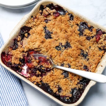 Top view of peach blueberry crisp with spoonful being removed