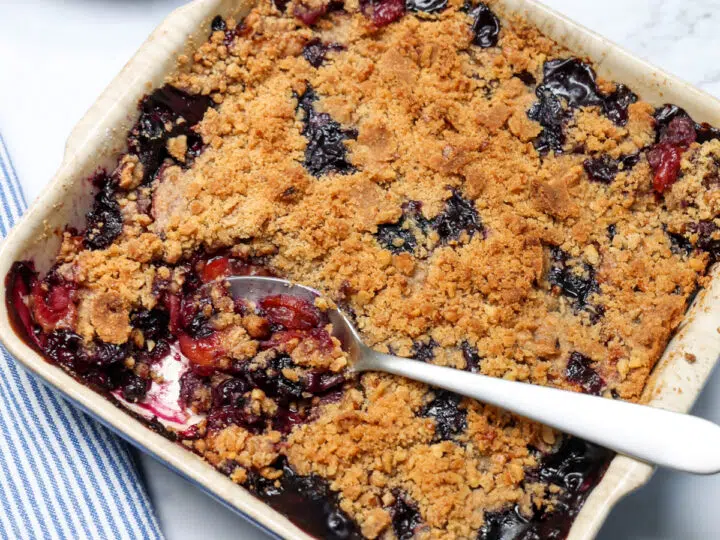 Top view of peach blueberry crisp with spoonful being removed