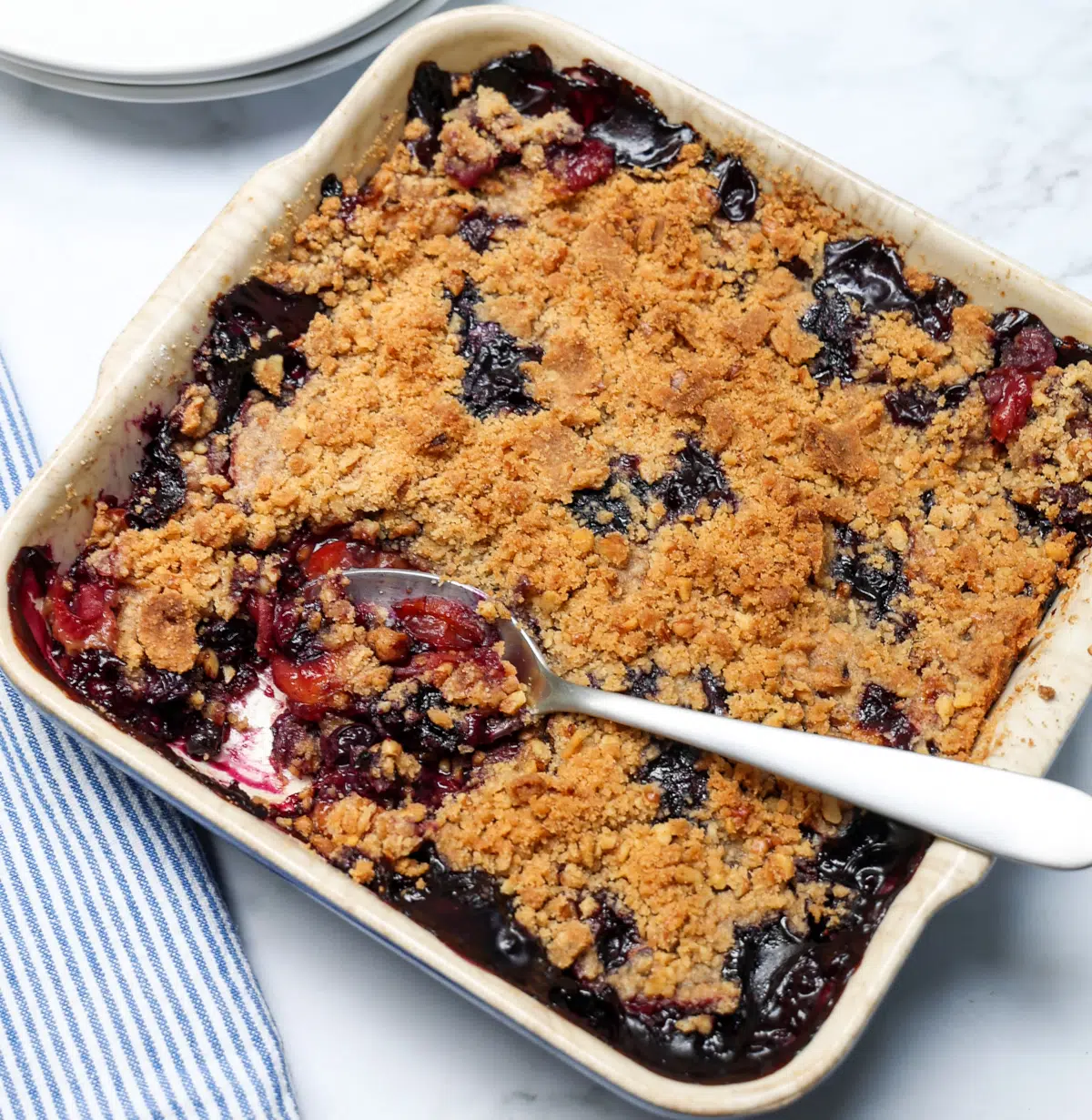 Top view of peach blueberry crisp with spoonful being removed