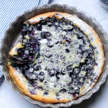 Overhead shot of blueberry clafoutis with scoop being removed.