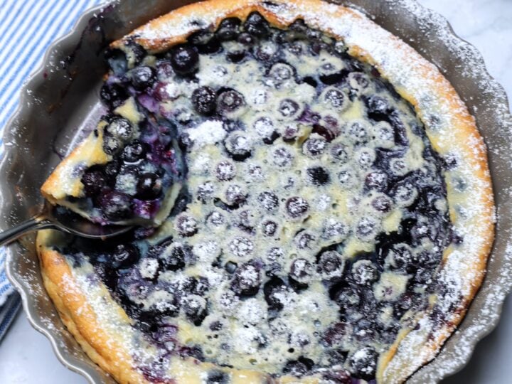 Overhead shot of blueberry clafoutis with scoop being removed.