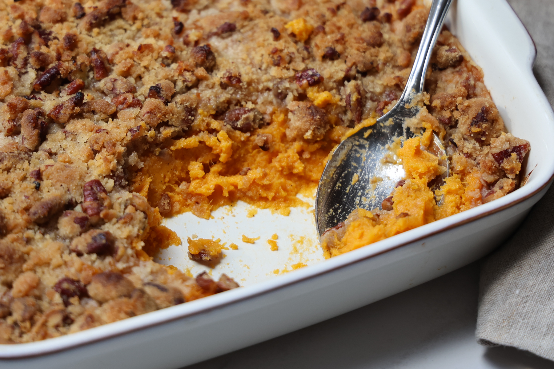Sweet potato souffle in white baking dish with spoonful removed.