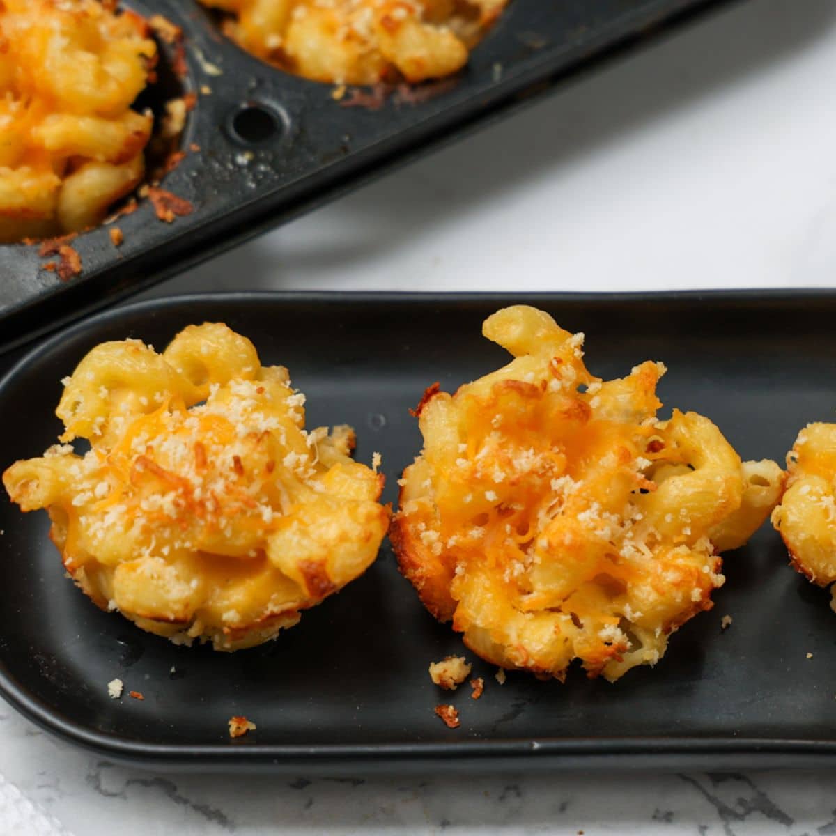Black platter with mac and cheese bites.