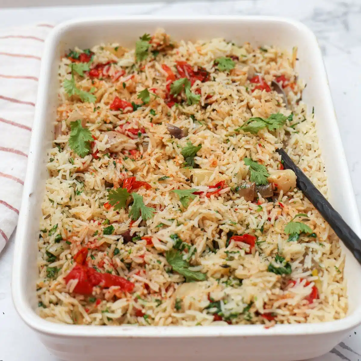 Baked Rice with roasted tomatoes and garlic in casserole dish. 